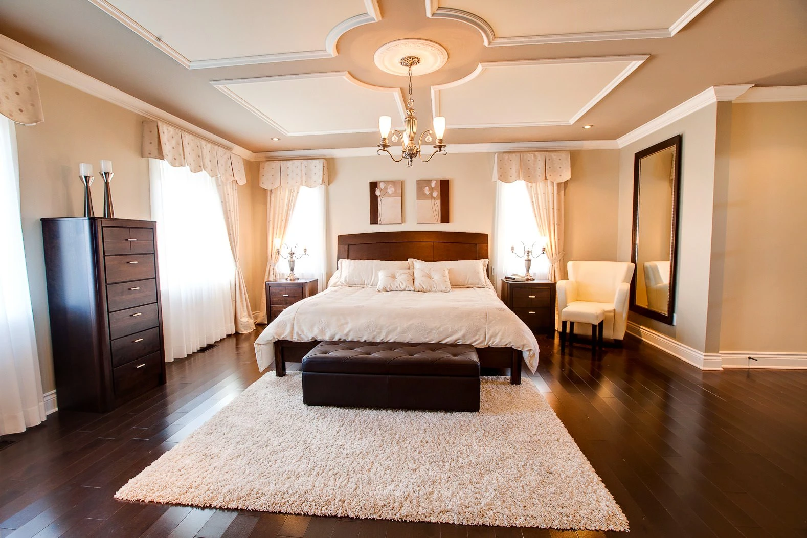Bright bedroom with a double bed, coffered ceiling and dark wood flooring