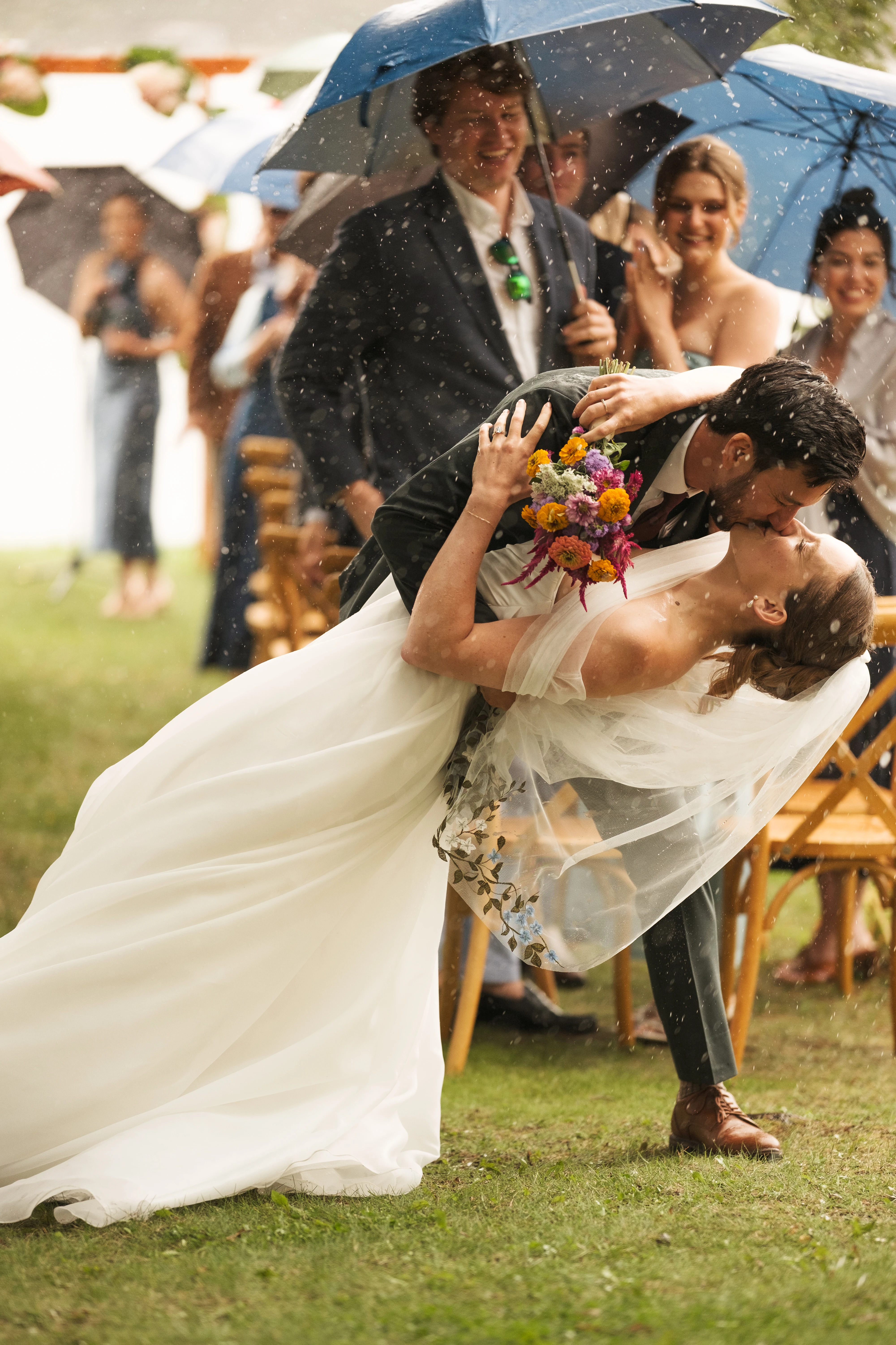 The newlyweds walk side by side across a lawn, smiling, in a black-and-white photograph