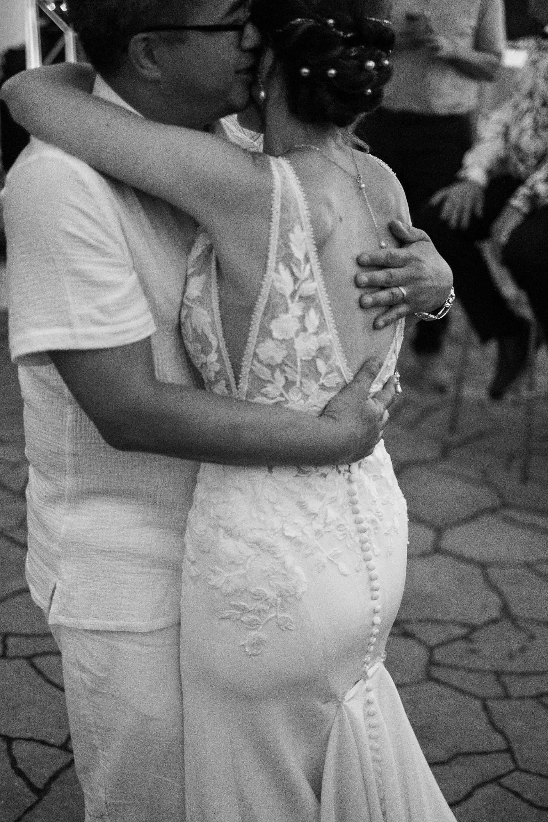 A black-and-white first dance framed on the lace back of the bride’s dress and the groom’s arms