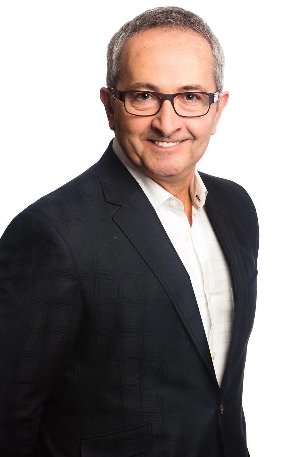 Grey-haired man in a dark blazer smiling against a white background