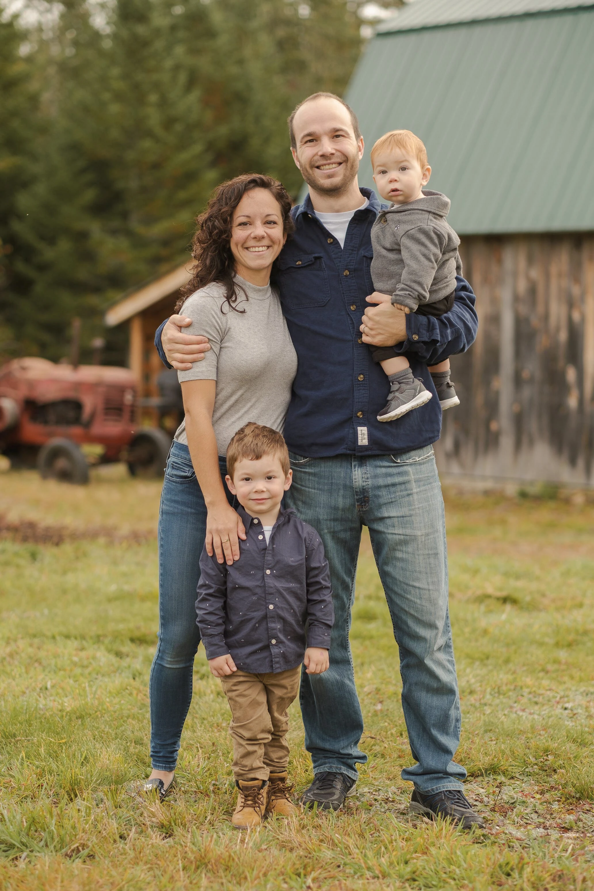 Two parents and their two young sons pose in front of a barn in the Laurentians
