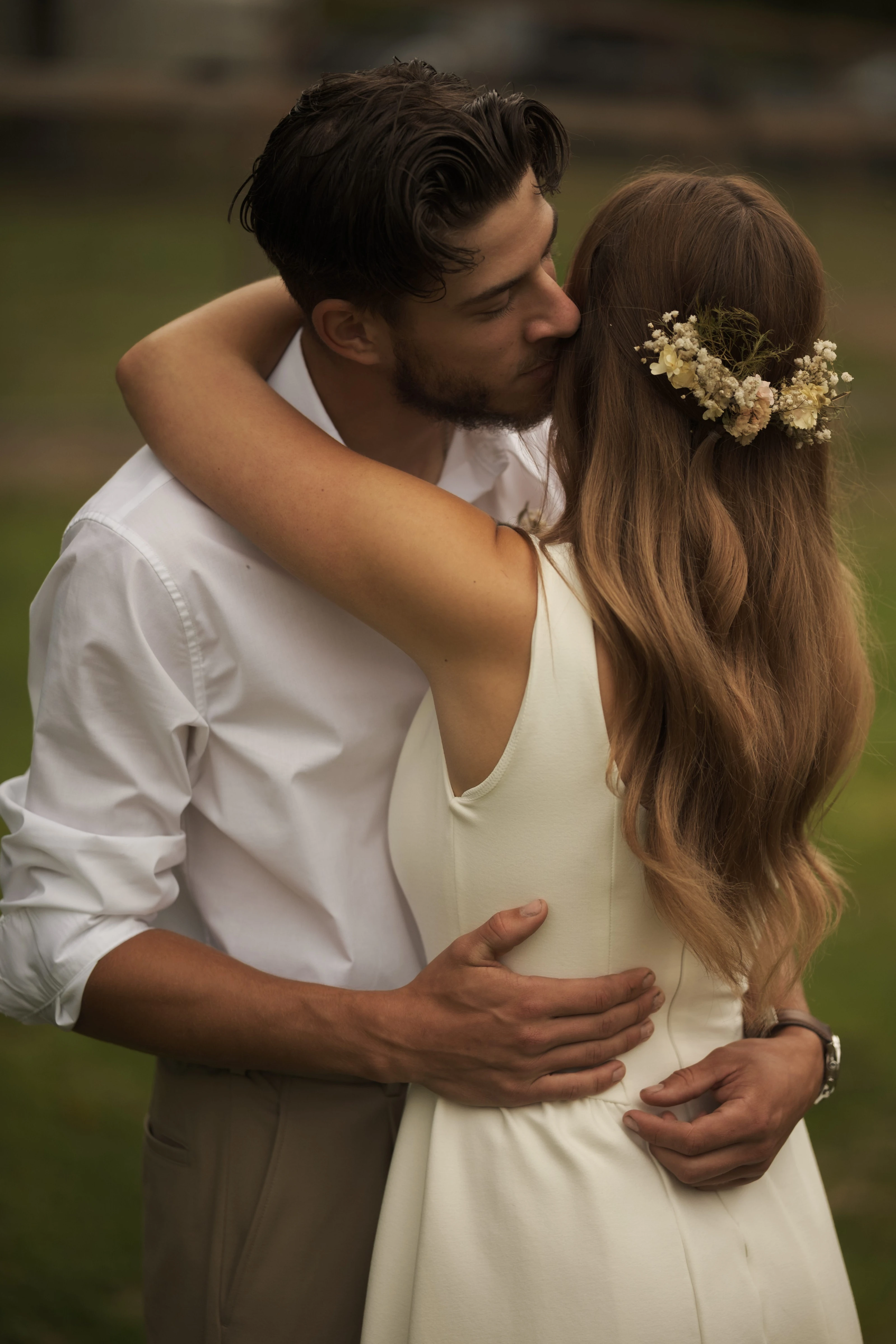 The newlyweds kiss in the woods beneath evening lights