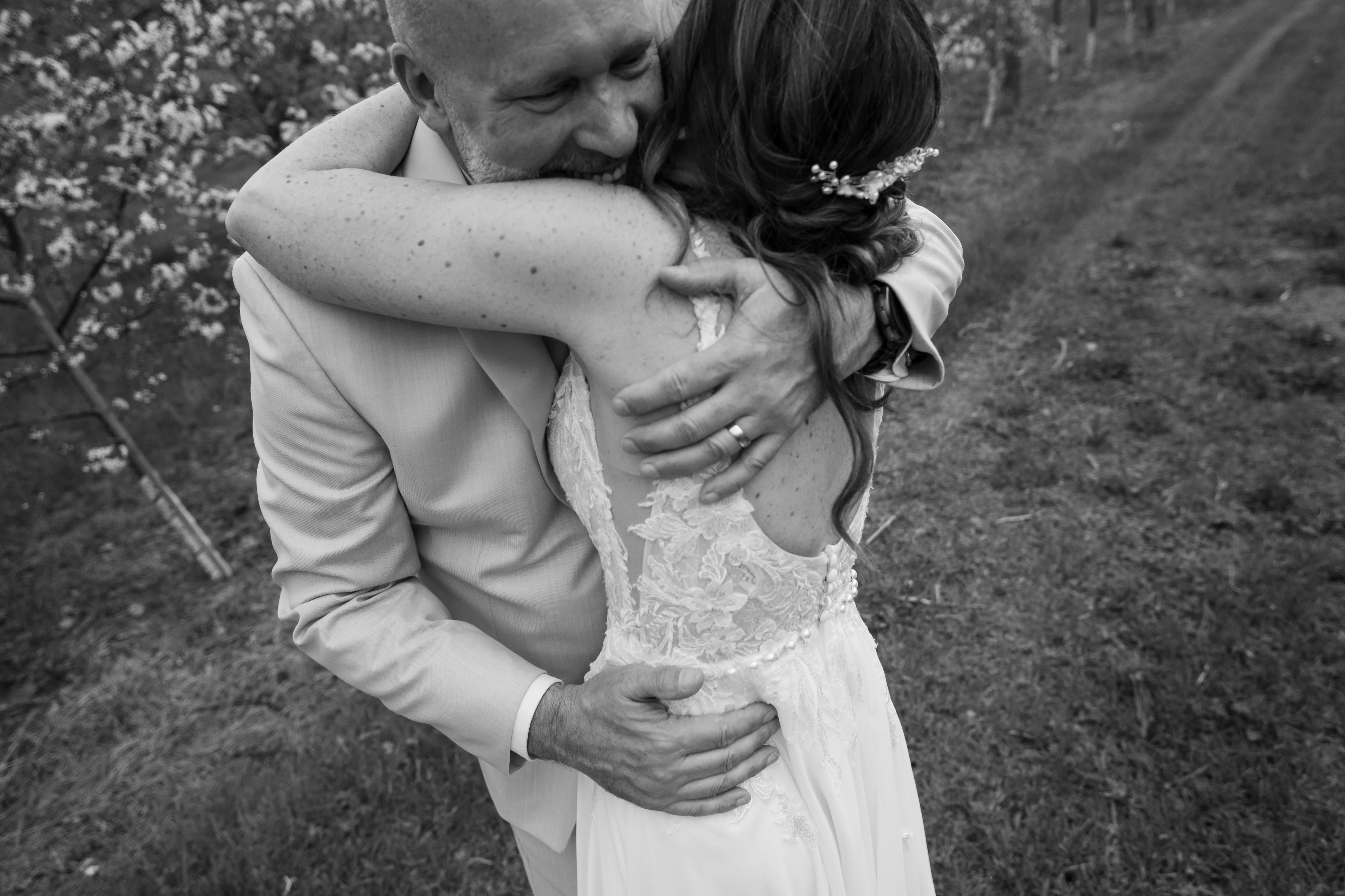 A mature newlywed couple laughing and embracing beneath maple trees with golden autumn leaves